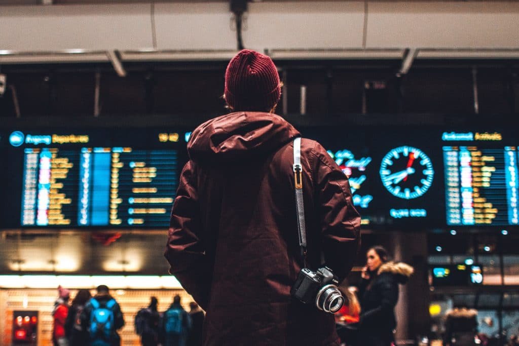 man standing infront of departure screen at airport