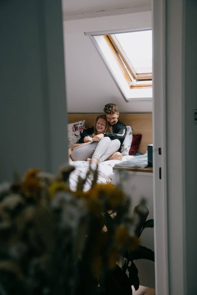 clothed couple cuddling on top of bed