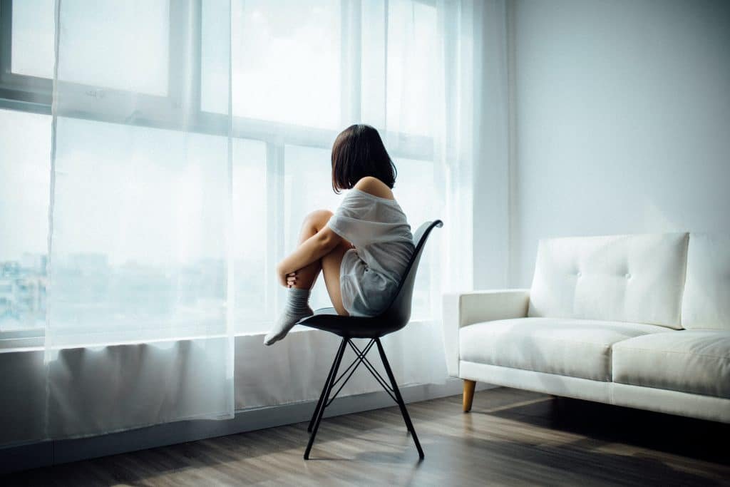 girl with short brown hair sitting on a chair staring out of the window