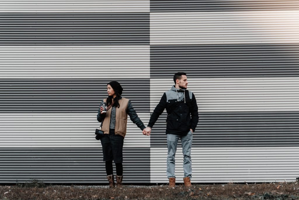 couple holding hands in front of a black and white wall