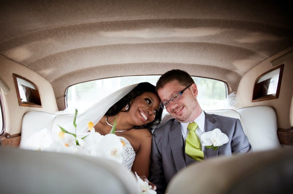 black female bride sitting in car next to white male groom
