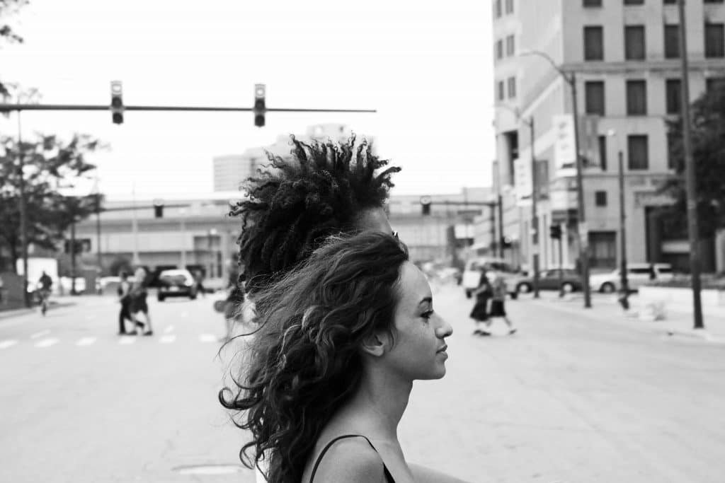 black and white woman with long hair man with afro behind her