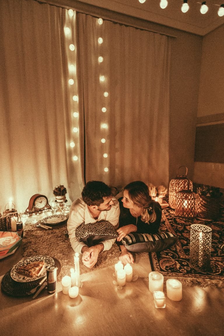 man and woman laying on floor with lit candles around them