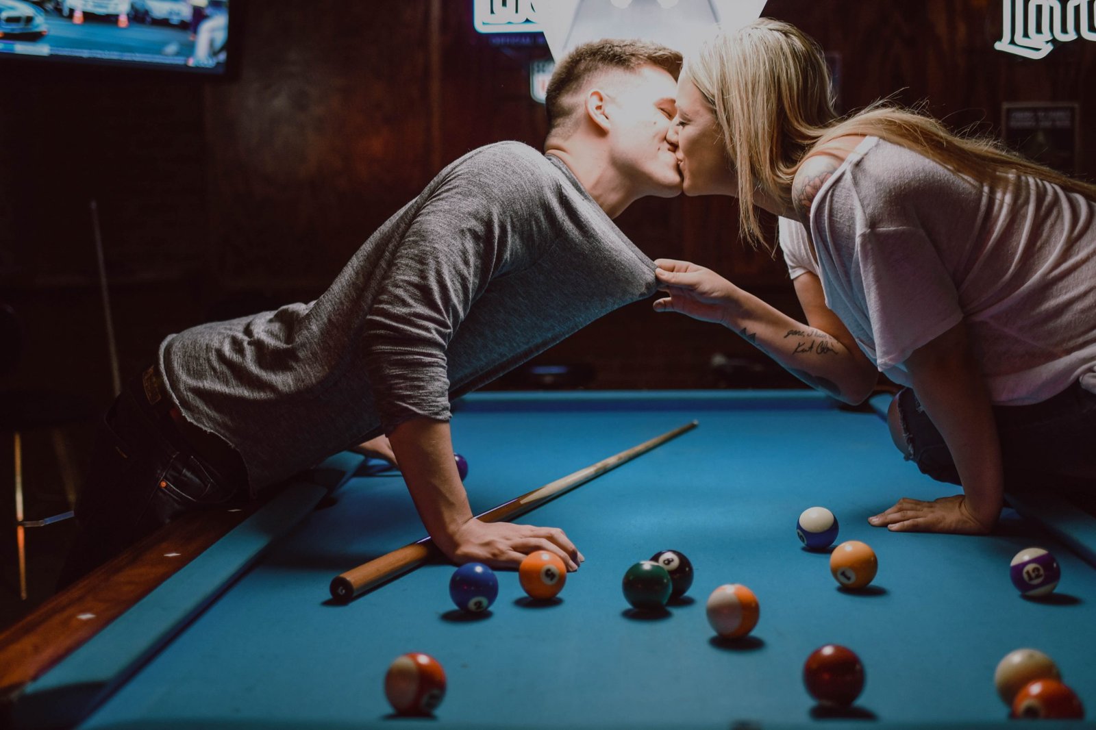 woman grabbing man kissing over pool table