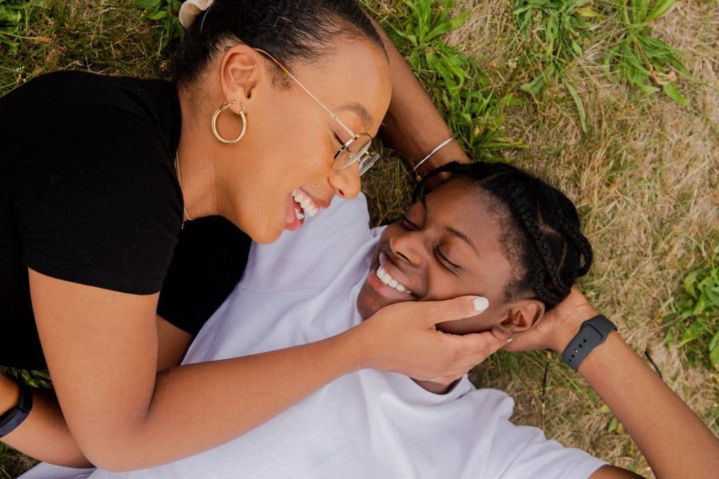 two black women laying in the grass smiling