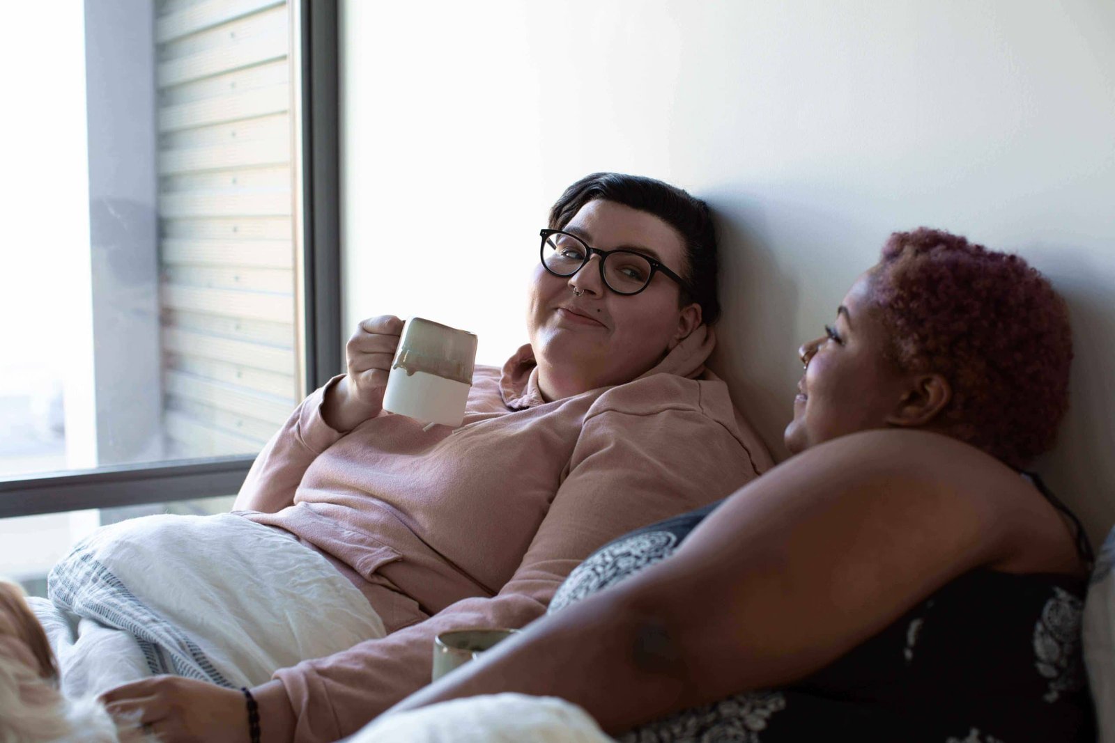 plus size female couple sitting in bed
