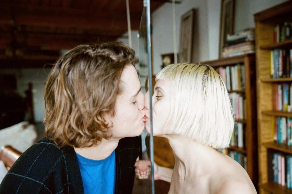 woman and man kissing with glass in between them